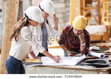 Two female  inspectors and architects discuss with 
 head engineer about construction project. Royalty-Free Stock Photo #714454864