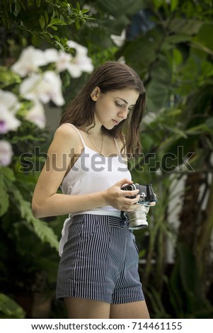 Teenage girl in a garden, taking pictures with a medium format vintage camera