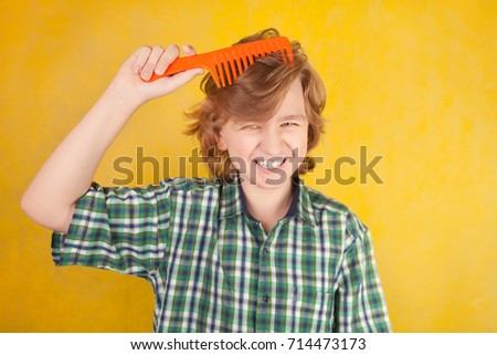 cute positive happy boy with big comb on yellow studio background