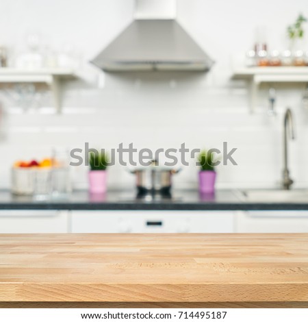 Blurred a wooden table top of the kitchen table on a blurry background of the kitchen interior. Bright interior decoration of home cooking. Bright ready-made picture for your individual design