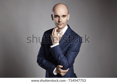 Portrait of young pensive businessman on gray background.