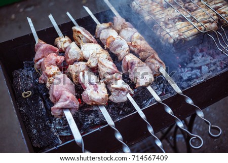 Grilled kebab cooking on metal skewers (grill). Roasted meat cooked at barbecue with smoke. Close up BBQ fresh pork meat chop slices. Traditional eastern dish, shish kebab.