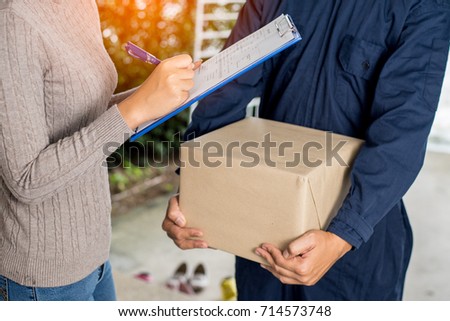 Woman customer signing receipt and receiving the parcel from delivery man. Business and logistic concept.