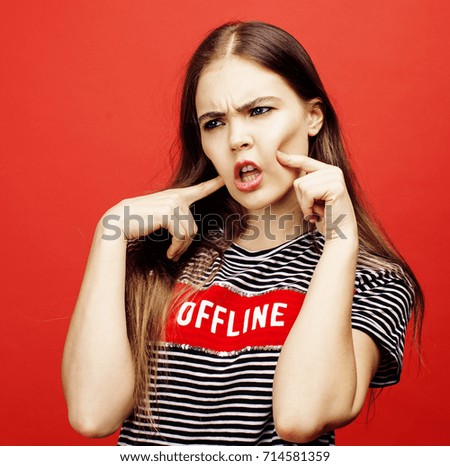 young pretty emitonal posing teenage girl on bright red background, happy smiling lifestyle people concept 