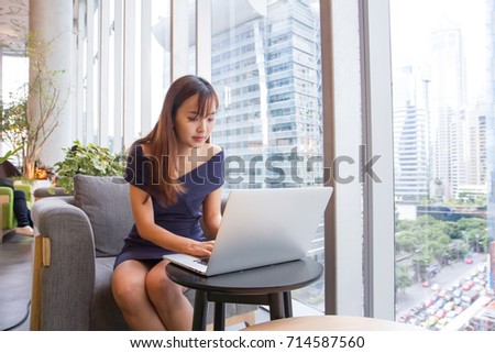Portrait of Beautiful asian girl using laptop computer while sitting on sofa in co-working space with the city background