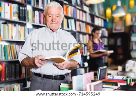 Mature man is choosing book in bookstore. 