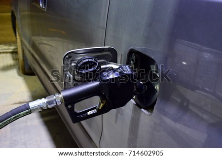 Refilling the car with fuel for silver van at the refuel station in the night