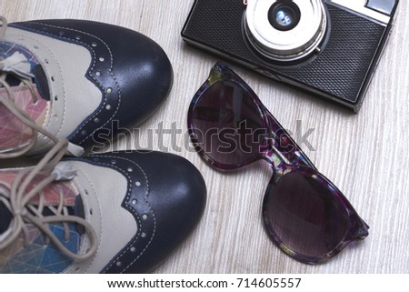 Colorful oxford female shoes, sunglesses and old analogue camera on wooden background, travel concept