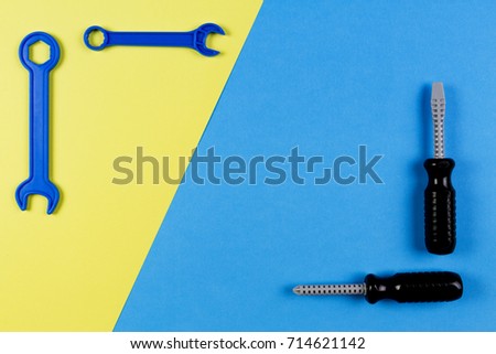 Toys background. Kids construction toys tools - colorful screwdrivers, screws and nuts on blue and yellow background.