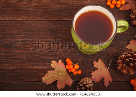 Autumn concept, fallen red-yellow leaves with apples, pine cones and a cup of tea on a wooden table. Thanksgiving Day.