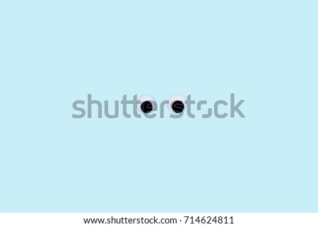 Googly eyes isolated on blue pastel background with space for text.Top view, flat lay