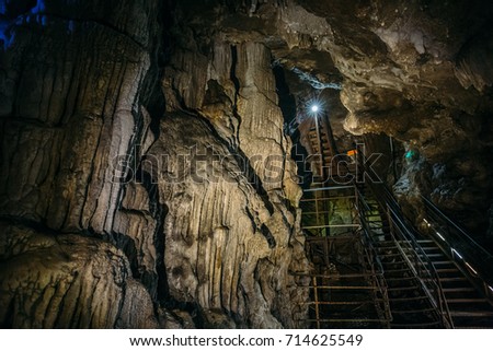 Iron ladder for descending into the tunnel of an underground cave with stalactites and stalagmites
