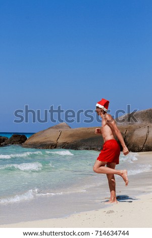 Christmas yoga man in red trousers and Christmas hat on the beach near the ocean. Similan Islands