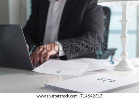 Scale and justice sign on pile of paper. Lawyer working in office. Attorney writing a legal document with laptop computer. Law firm and business concept. Royalty-Free Stock Photo #714642313