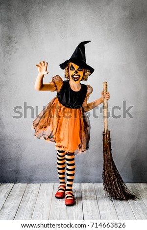 Funny child dressed witch costume. Kid painted terrible pumpkin. Halloween autumn holiday concept
