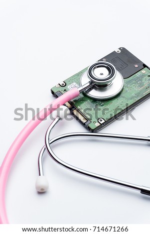 Hard disk drives and stethoscope on white background. Computer technology concept