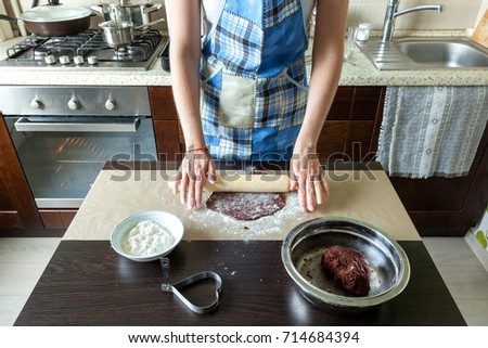 a woman in a home kitchen makes a dough to bake a biscuit, rolls out the dough for a chocolate chip cookie