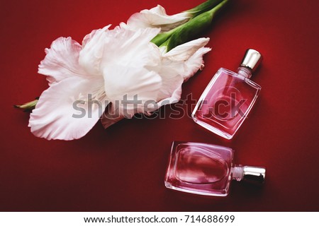 Perfume bottles with flowers on red background. Perfumery, cosmetics, fragrance collection.