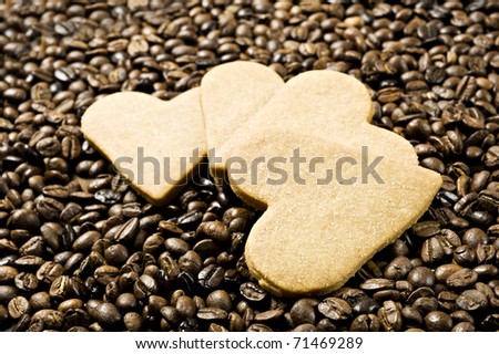 Close up background of a sugar coated heart shaped cookies in coffee beans with very shallow depth of field and intentional low light