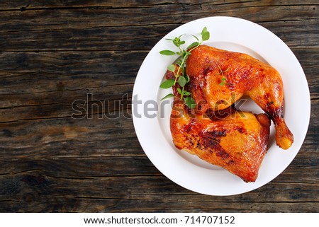 roasted chicken leg quarters with crispy golden brown skin with fresh green thyme leaves on white plate on dark wooden boards, view from above Royalty-Free Stock Photo #714707152