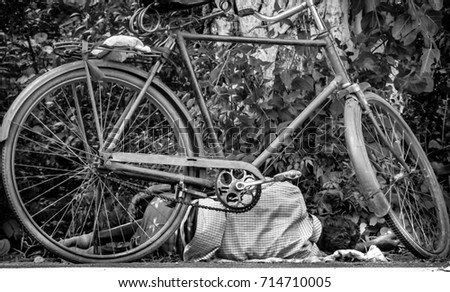 Picture of a homeless man sleeping on the road by his cycle.