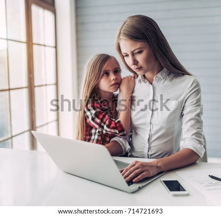 I'm busy! Beautiful young woman is working at home with her little cute daughter nearby. Don't have enough time for child.