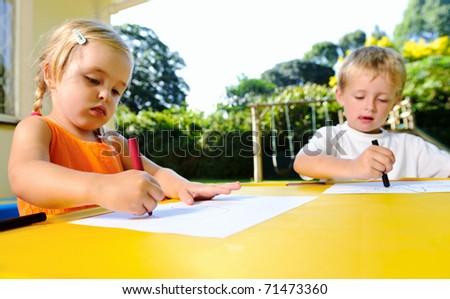 cute adorable young kids with crayons at an outside playschool