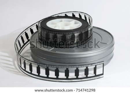 Motion picture film roll lying on top of a film canister.