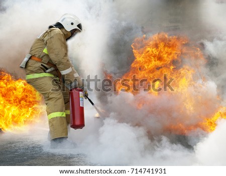 Extinguishing a major fire. A professional fireman in a special suit extinguishes an open fire with a fire extinguisher.