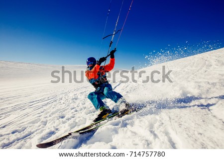  Skier with a kite on fresh snow in the winter in the tundra of Russia against a clear blue sky. Teriberka, Kola Peninsula, Russia. Concept of winter sports snowkite on ski. Royalty-Free Stock Photo #714757780