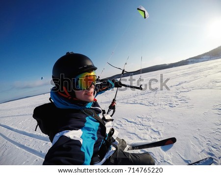 man ski on snow kite holds an action camera and takes a picture of Selfie.