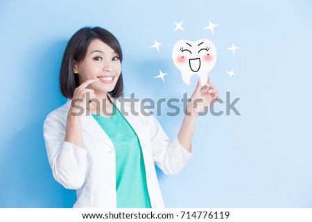 woman dentist take tooth board and touch her teeth on the blue background