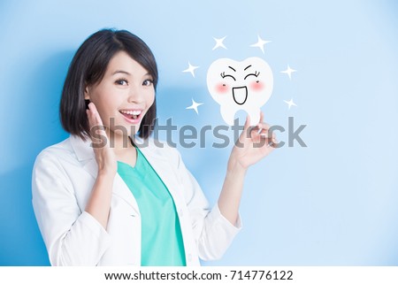 woman dentist take tooth board and feel excited on the blue background