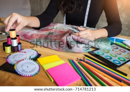 Beautiful young fashion designer woman choosing thread for sewing clothes with sewing machine