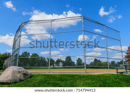 Beautiful day at a baseball catcher's fence and field with blue skies, fluffy clouds, green grass and large border surround by trees at a park in Kentucky  Summer 2018 