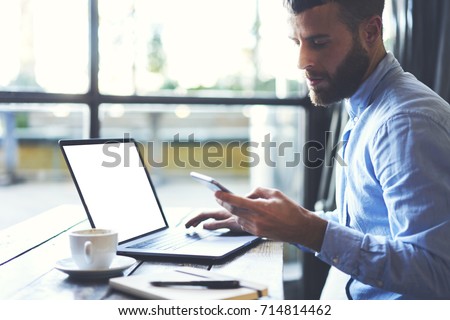 Young successful businessman reading received sms message from colleague while working at modern laptop computer with copy space area for advertising text message Royalty-Free Stock Photo #714814462