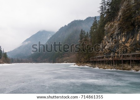 Cold river over the mountains. A frozen river over the mountains. Winter mountains over the ice river. Mountains above the sky