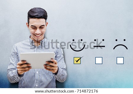 Customer Experience Concept, Happy Businessman holding digital Tablet with a checked box on Excellent Smiley Face Rating for a Satisfaction Survey Royalty-Free Stock Photo #714872176