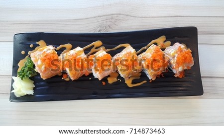 Sushi rolls with salmon on tray, on wooden background
