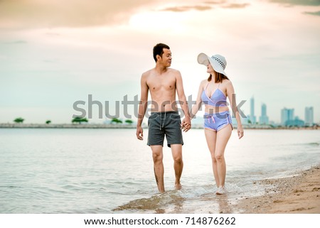 Asian couple walking on the beach when the sun is about to sunset during the honeymoon. There are  Couple walking on Valentine's Day