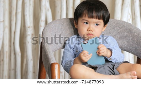 Little son holding cellphone and feeling angry