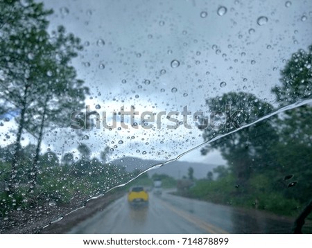 Raindrops on the windshield cause poor visualization and dangerous driving during rainy and slippery road.View from car seat.