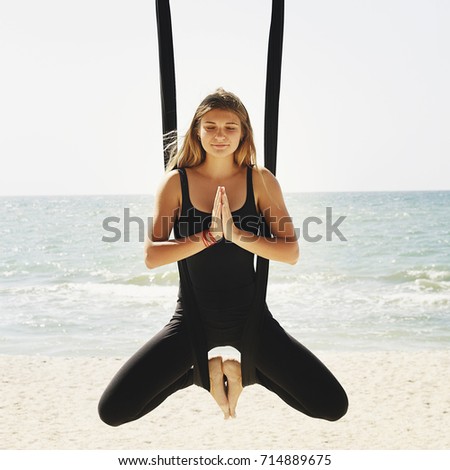 young beautiful brunette woman doing fly yoga. Sitting in hammock with namaste gesture. Wellness and healthy concept.