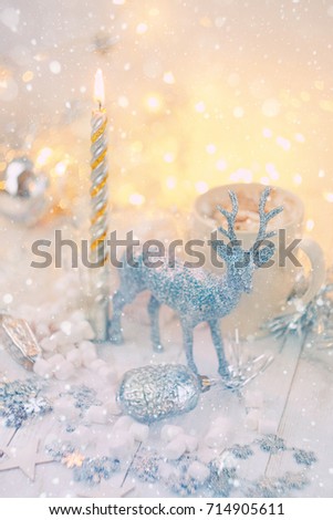 Christmas and New Year holidays concept. Decorative toy deer, cup of coffee, christmas toys and candle on table, abstract shiny background. festive winter season. beautiful Christmas composition. 