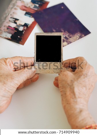 Old woman holding picture in hand.