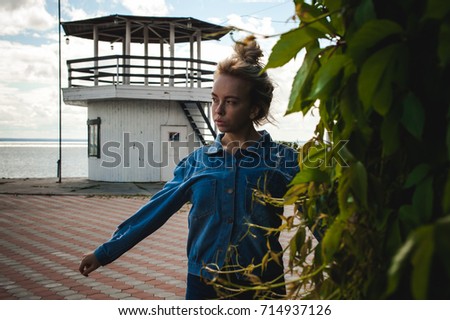 young beautiful woman in jeans clothes outdoors. portrait of a girl with freckles on her face, stylish girl on sea beach, on a sunny summer autumn day.