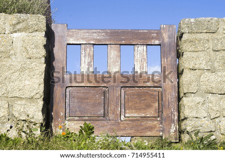 Cute wooden wicket of a rural house in a stone wall against a blue sky