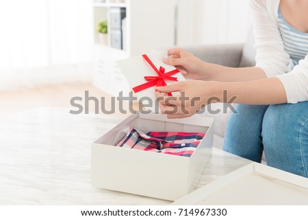closeup photo of woman preparing to open bow tie reading card when she sitting on sofa received personal birthday gift package.
