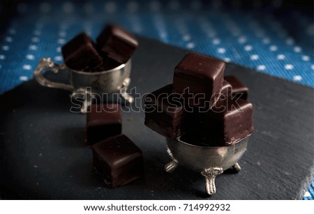 a lot of chocolate pralines on stone table on blue background.chocolate sweets