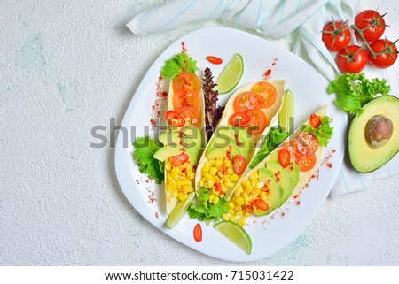 Tacos tortilla with vegetables - tomatoes, avocado. corn, pepper and spices on a plate and light background